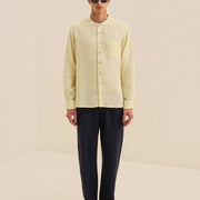 Man wearing a light yellow shirt and black pants on a beige background