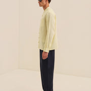 Man wearing a light yellow shirt and dark pants on a beige background
