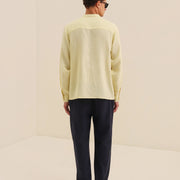 Person wearing a light yellow sweater and dark pants on a beige background
