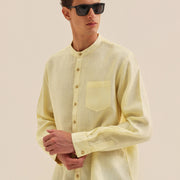 Man wearing a light yellow long-sleeve shirt with a pocket on a beige background