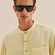 Man wearing a light yellow shirt with a neutral background